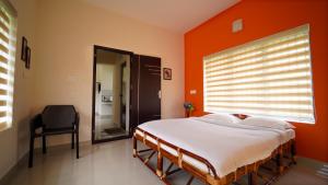 a bedroom with a large bed with an orange wall at Vrindhavan Mist City Resorts in Kanthalloor