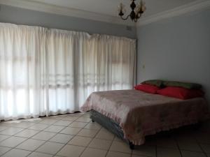 - une chambre avec un lit doté d'oreillers et de rideaux rouges dans l'établissement Ezrom bright, à Port Shepstone