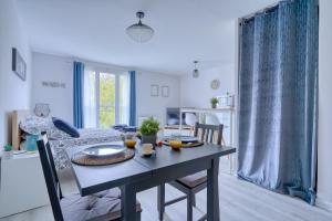 a dining room and living room with a table and chairs at Logement Elora in Courcouronnes