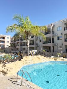 a swimming pool with a palm tree in front of a building at Royal Seacrest new apartment B G2 ground floor in Paphos
