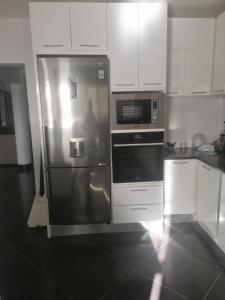 a kitchen with a stainless steel refrigerator and white cabinets at Cova da Inglesia in Mindelo