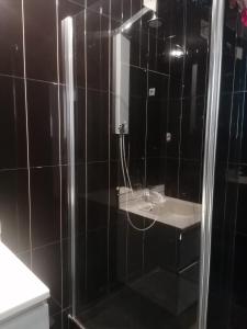 a black tiled bathroom with a shower and a sink at Cova da Inglesia in Mindelo