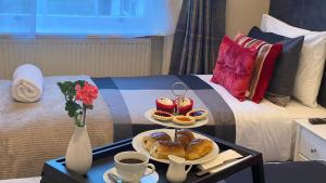 a hotel room with a bed with two plates of pastries at Prime Inn in London