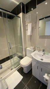 y baño con ducha, aseo y lavamanos. en Prime Inn, en Londres