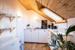 クラーゲンフルトにあるAPARTMENT KLAGENFURT - Apartment Wulfeniaの白いキャビネットと木製の天井が備わるキッチン
