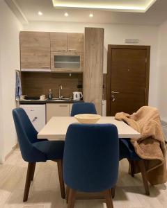 a dining room table with blue chairs and a kitchen at Milmari S50 in Kopaonik