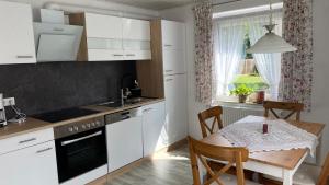 a kitchen with white cabinets and a table and a window at Ferienwohnung Schmid in Lautrach