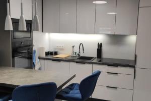 クラクフにあるNowoczesny apartament w pobliżu centrumのキッチン(白いキャビネット、青い椅子付) +15枚の写真