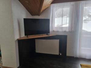 een flatscreen-tv op een standaard in een kamer met een raam bij Apartment Konrad in Umhausen