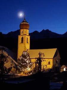 une église avec un arbre de Noël devant elle la nuit dans l'établissement Apartment Konrad, à Umhausen