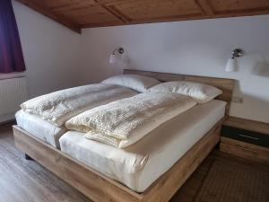 - un lit avec des couvertures blanches et des oreillers dans l'établissement Apartment Konrad, à Umhausen