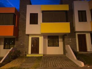 un edificio con una fachada de color amarillo y blanco con una puerta en Arriendo casa de dos pisos, en Quito