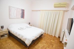 a bedroom with a white bed and a television at acropolis super cosy apartment in Athens