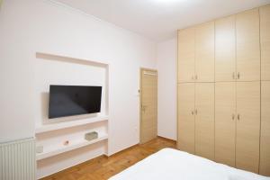 アテネにあるacropolis super cosy apartmentの白い壁のベッドルーム(テレビ付)