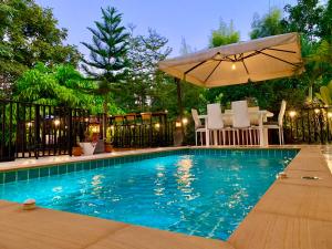 a swimming pool with an umbrella and a table and chairs at Bonnie Baan Private Pool Villa, Mae Rim in Mae Rim