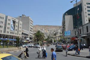 un grupo de personas cruzando una concurrida calle de la ciudad en YCC Guesthouse, en Nablus