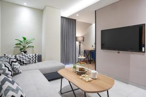 a living room with a couch and a tv on a wall at Cordela Suites Tasikmalaya in Tasikmalaya