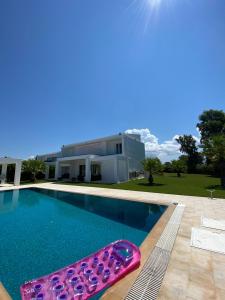 a swimming pool with a pink and purple pool toy in front of a house at Greek Villas Justine View Beach in Kyllini