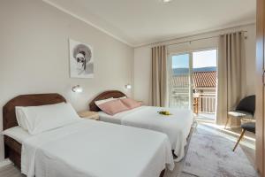 a hotel room with two beds and a window at Apartmani Vico in Herceg-Novi