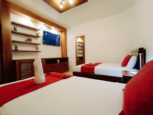 1 dormitorio con 2 camas y silla roja en El Arco de Darwin, en Puerto Ayora