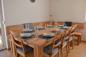 uma mesa de madeira com cadeiras e pratos e copos de vinho em Holiday Home Znojmo w/ Wellness & Wine em Znojmo