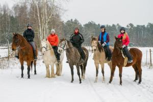 um grupo de pessoas montando cavalos na neve em Kolorowe Wzgórze agroturystyka i konie em Trojanów