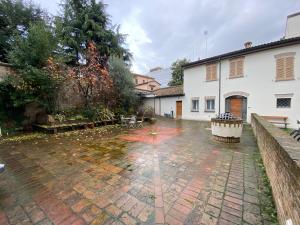 a courtyard with a brick floor and a white building at Les Tres Chic in Cesena
