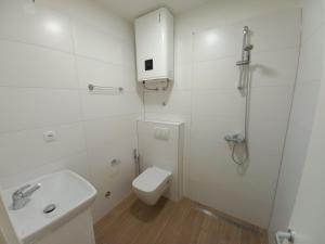 a white bathroom with a toilet and a sink at Studio Apartman Bambi in Pale