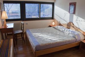 a bedroom with a bed and a desk and two windows at Apartments Casa Trasparente in Arcugnano