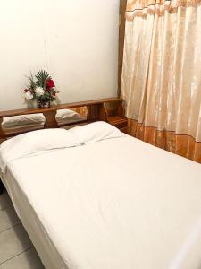 a bedroom with a white bed with a vase of flowers at Apartamento in Aguas Zarcas