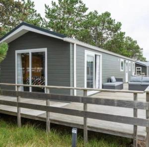 a gray tiny house with a large deck at Ibiza huisje in Den Hoorn