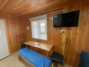 Habitación con escritorio y TV en una pared de madera. en Cabañas Pacífico - Faro Corona, en Ancud
