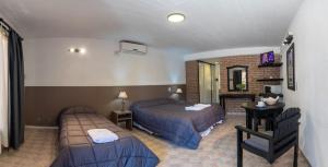 ein Hotelzimmer mit zwei Betten und einem Tisch in der Unterkunft Hotel La Colina del Sol in Villa Carlos Paz + 36 Fotos