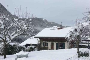 una casa cubierta de nieve frente a una montaña en A l’Abri du Leschaux, en Le Petit-Bornand-lès-Glières