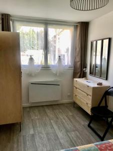 een kamer met een bureau, een raam en een dressoir bij Maisonnette de charme au calme près des bords de Marnes in Saint-Maur-des-Fossés