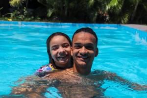 a man and a girl in a swimming pool at Pousada Mansão Férias in Cabo Frio