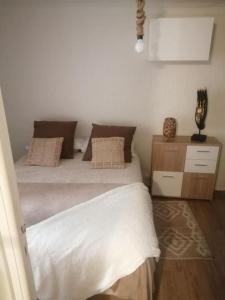 1 dormitorio con 1 cama con sábanas y almohadas blancas en appartement cosy situé à 2mn de la plage à pied climatise, en Villefranche-sur-Mer