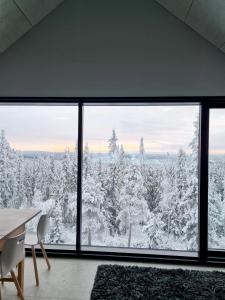 a room with a view of a snow covered forest at Huvila Hukanhuippu in Syöte
