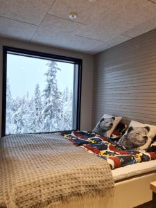 a bedroom with a bed and a large window at Huvila Hukanhuippu in Syöte +16 photos