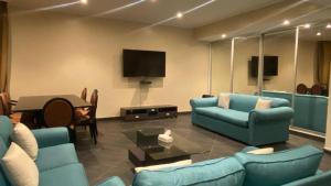 sala de estar con muebles azules y TV de pantalla plana en Bana Bana Resort en Durat  Alarous