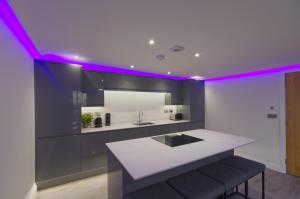 a kitchen with a white counter and purple lighting at Marina Walk, New Luxury Coastal Apartment in The English Riviera, close to the Shops, Bars and Restaurants with Torquay Marina and Torre Abbey Sands Beach a short walk away! in Torquay