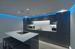 a kitchen with a white counter and blue lighting at Marina Walk, New Luxury Coastal Apartment in The English Riviera, close to the Shops, Bars and Restaurants with Torquay Marina and Torre Abbey Sands Beach a short walk away! in Torquay