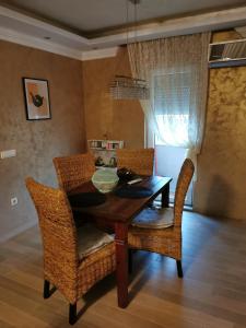 uma sala de jantar com uma mesa de madeira e cadeiras de vime em Lux apartman Lena em Belgrado
