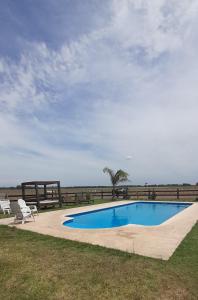 einen Pool mit zwei Stühlen am Meer in der Unterkunft Cabañas El Encuentro Lobos in Salvador María