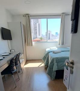 a bedroom with a bed and a desk and a window at Studio completo ao lado do metrô Brás in São Paulo