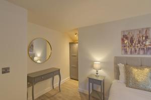 a bedroom with a bed and a table and a mirror at Marina Walk, New Luxury Coastal Apartment in The English Riviera, close to the Shops, Bars and Restaurants with Torquay Marina and Torre Abbey Sands Beach a short walk away! in Torquay