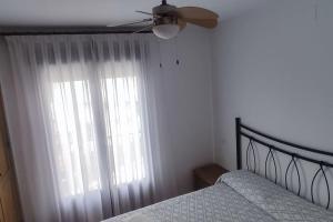1 dormitorio con 1 cama, ventilador de techo y ventana en El casillo, en El Arenal