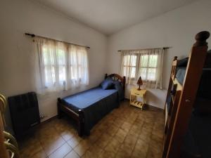 a bedroom with a bed and two windows at Otto's Haus in Villa General Belgrano