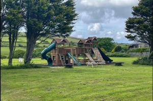 einen Spielplatz mit Rutsche auf dem Feld in der Unterkunft Wheal Tor- Beautifully Fitted Wooden Lodge Helston Cornwall in Helston