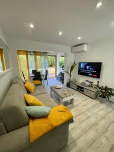 a living room with a couch and a flat screen tv at A1 LA PLAGE D'OR in Le Lavandou